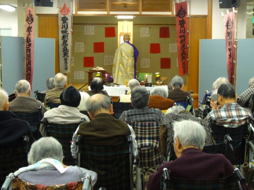 豊寿苑内での祈祷の様子。奥は未年を迎えたご利用者名で紅白の布を奉納。